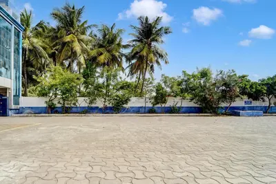 a basketball court in front of a building with palm trees at Super Hotel O Tiruppur Near Railway station in Tiruppūr