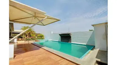 a swimming pool with an umbrella in a house at Horizon Heights Apartment in Coimbatore