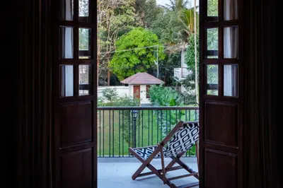 an open door with a bench on a balcony at Reverie in North Paravur