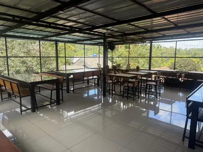 a dining room with tables and chairs and windows at 2 Empire One Bedroom with Common Pool in Wayanad