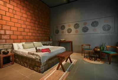 a bedroom with a bed and a brick wall at Rustic Nestle, Tirupur in Tiruppūr