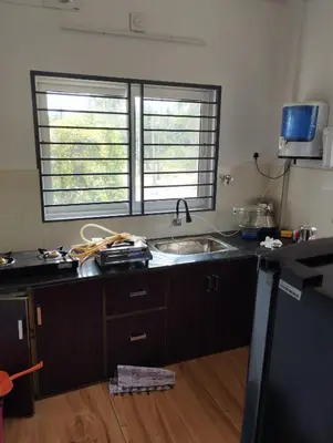 a kitchen with a sink and a counter with two windows at Thrikarthika appartments in Guruvāyūr