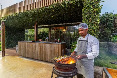 a man cooking food in a pot on a grill at Finch,Kotagiri in Kotagiri