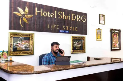 a man sitting at a desk talking on a cell phone at Hotel DRG Heritage in Tiruppūr
