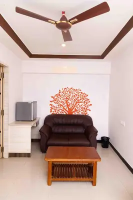 a living room with a couch and a ceiling fan at Hotel DRG Heritage in Tiruppūr