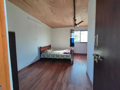a bedroom with a bed in a room with a wooden floor at Bandipur Jaguar Homestay in Bandipūr