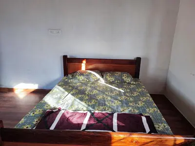 a bed with a wooden frame with a quilt on it at Bandipur Jaguar Homestay in Bandipūr