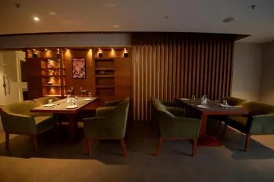 a dining room with two tables and green chairs at Ambal Regency in Pudukād