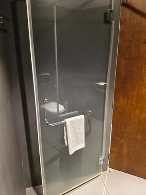a bathroom with a glass door with a towel rack at Ambal Regency in Pudukād