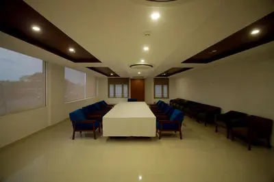 a conference room with a white table and blue chairs at Ambal Regency in Pudukād