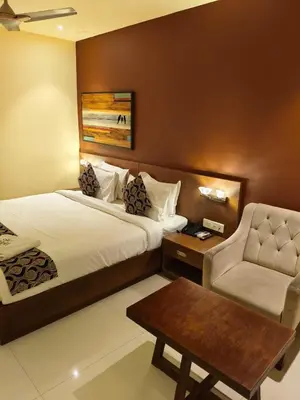 a hotel room with a bed and a chair at Ambal Regency in Pudukād