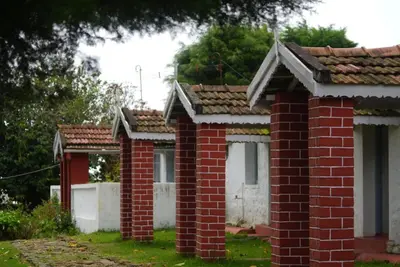 a row of brick buildings with trees in the background at Estate Bungalow with Waterfall, Mountain & Valley Views in Kotagiri