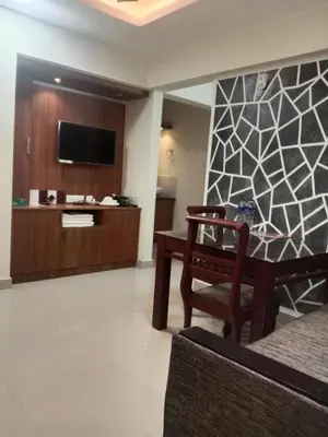 a living room with a table and a tv at Airport Tree in Nedumbassery