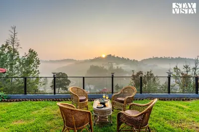 a patio with chairs and a table with a view at StayVista at Valley Whispers with BBQ & Bonfire in Ooty