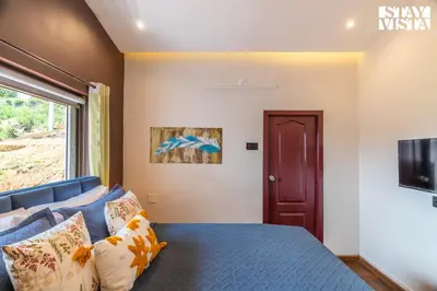a bedroom with a blue bed and a window at StayVista at Valley Whispers with BBQ & Bonfire in Ooty