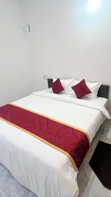 a large white bed with red pillows on it at Portico Resorts in Pandalūr
