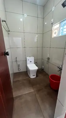 a bathroom with a toilet and a red bucket at Portico Resorts in Pandalūr