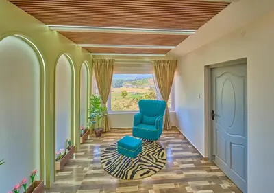 a hallway with a blue chair and a window at Vihani's Western Clouds Ooty by VOYE HOMES - Peaceful Getaway Near Avalanche Emerald Lake in Ooty