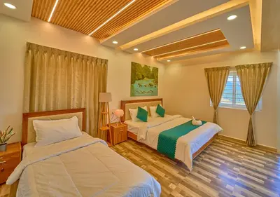 a bedroom with two beds and a window at Vihani's Western Clouds Ooty by VOYE HOMES - Peaceful Getaway Near Avalanche Emerald Lake in Ooty