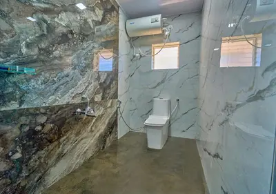 a bathroom with a toilet and a stone wall at Vihani's Western Clouds Ooty by VOYE HOMES - Peaceful Getaway Near Avalanche Emerald Lake in Ooty
