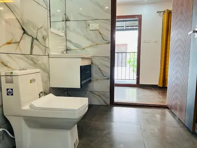a bathroom with a toilet and a marble wall at 3 Empire One Bedroom with Common Pool in Wayanad