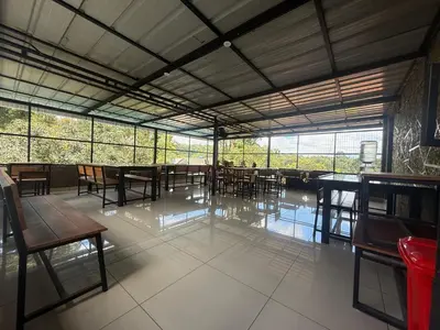 a dining room with tables and chairs and windows at 3 Empire One Bedroom with Common Pool in Wayanad