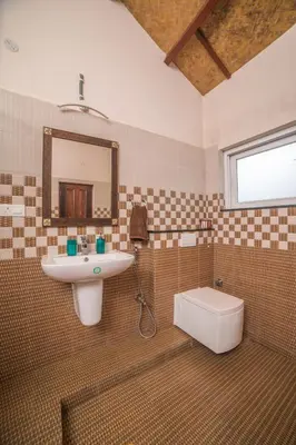 a bathroom with a sink and a toilet and a mirror at Onella in Yedapalli