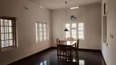 a dining room with a table and chairs and windows at greenview homestay Mayyil in Parassinikadavu