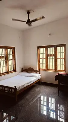 a bedroom with a bed and a ceiling fan at greenview homestay Mayyil in Parassinikadavu