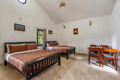 a bedroom with two beds and a table and a desk at Interlaken in Yedapalli