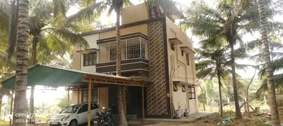 a car parked in front of a building with palm trees at KV Farm house in Malaiyāndipattanam