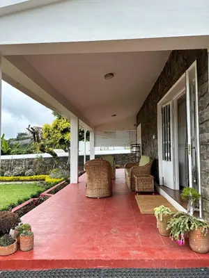 an outdoor patio with wicker chairs and a porch at Ivy Cottage Kodaikanal in Kodaikānāl