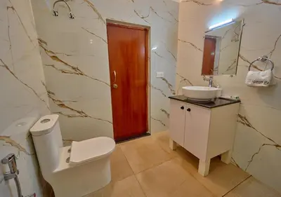 a bathroom with a toilet and a sink and a mirror at Central Homestay Ooty by VOYE HOMES Family-Friendly Budget Stay with Valley And Mountain Views in Ooty