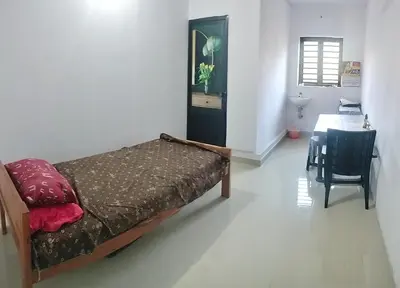 a bedroom with a bed and a table in a room at Aswathy Bhavan in Palakkad