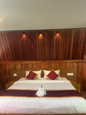 a bedroom with a large bed with wooden walls at River Valley Huts, Wayanad in Panamaram