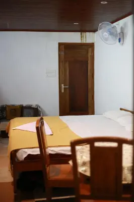 a room with a bed and a chair and a door at Dreams Valley in Kadavoor