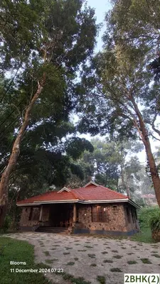 a stone building with a red roof and trees at Stone Villa in Blooms Green Farm in Wayanad
