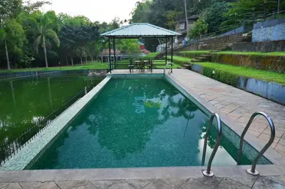 a pool with a table and a gazebo at Stone Villa in Blooms Green Farm in Wayanad