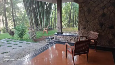 a room with two chairs and a stone wall at Stone Villa in Blooms Green Farm in Wayanad