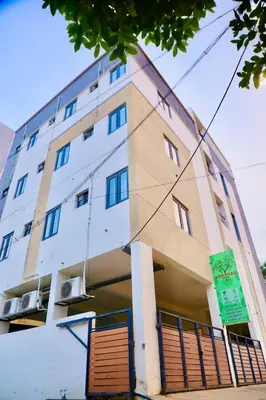 a tall white building with a green sign on it at Virksham Hotel in Coimbatore