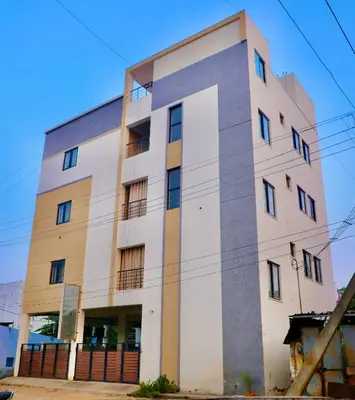 a tall white building with a lot of windows at Virksham Hotel in Coimbatore