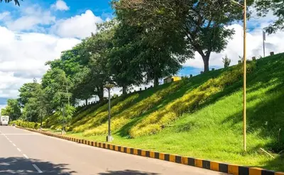 a grassy hill with trees on the side of a road at Laura Airport Suits & Apartments in Nedumbassery