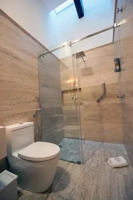 a bathroom with a toilet and a glass shower at Laura Airport Suits & Apartments in Nedumbassery
