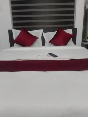 a bed with red pillows and a remote control on it at calicut residency in Kozhikode