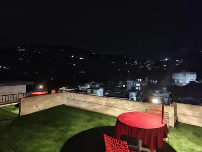 a red table and chairs on a balcony at night at Jazz&Hill in Kodaikānāl