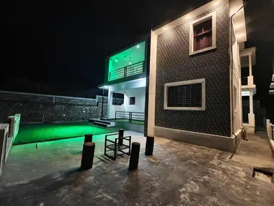 a building with a green swimming pool at night at Jazz&Hill in Kodaikānāl