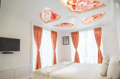 a bedroom with orange curtains and a bed and a tv at Sepoy Grande Mysore in Mysore