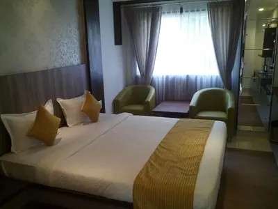 a bedroom with a bed with two chairs and a window at Sepoy Grande Mysore in Mysore