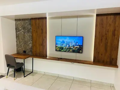a tv on a wall with a table and a chair at Royal Plaza Inn by RAK Rooms, Calicut in Kozhikode