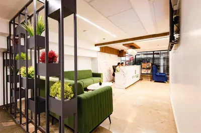 a living room with a green couch and plants at Royal Plaza Inn by RAK Rooms, Calicut in Kozhikode